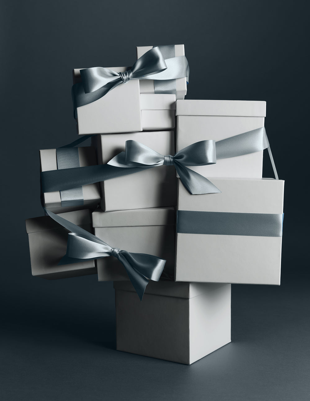 Stacked white gift boxes tied with grey-blue satin ribbons – MATE the Label holiday