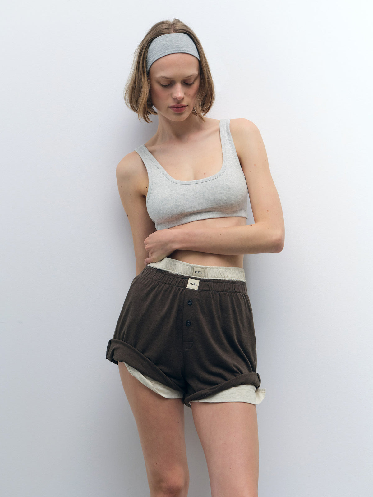 Woman in a light grey organic cotton scoop bralette and dark brown shorts with a light waistband.