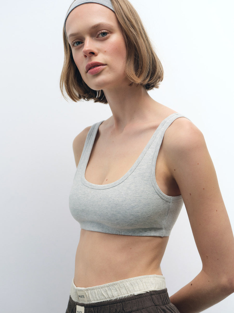 Woman wearing a light grey Organic Comfort Scoop Bralette and matching headband, with dark pants.