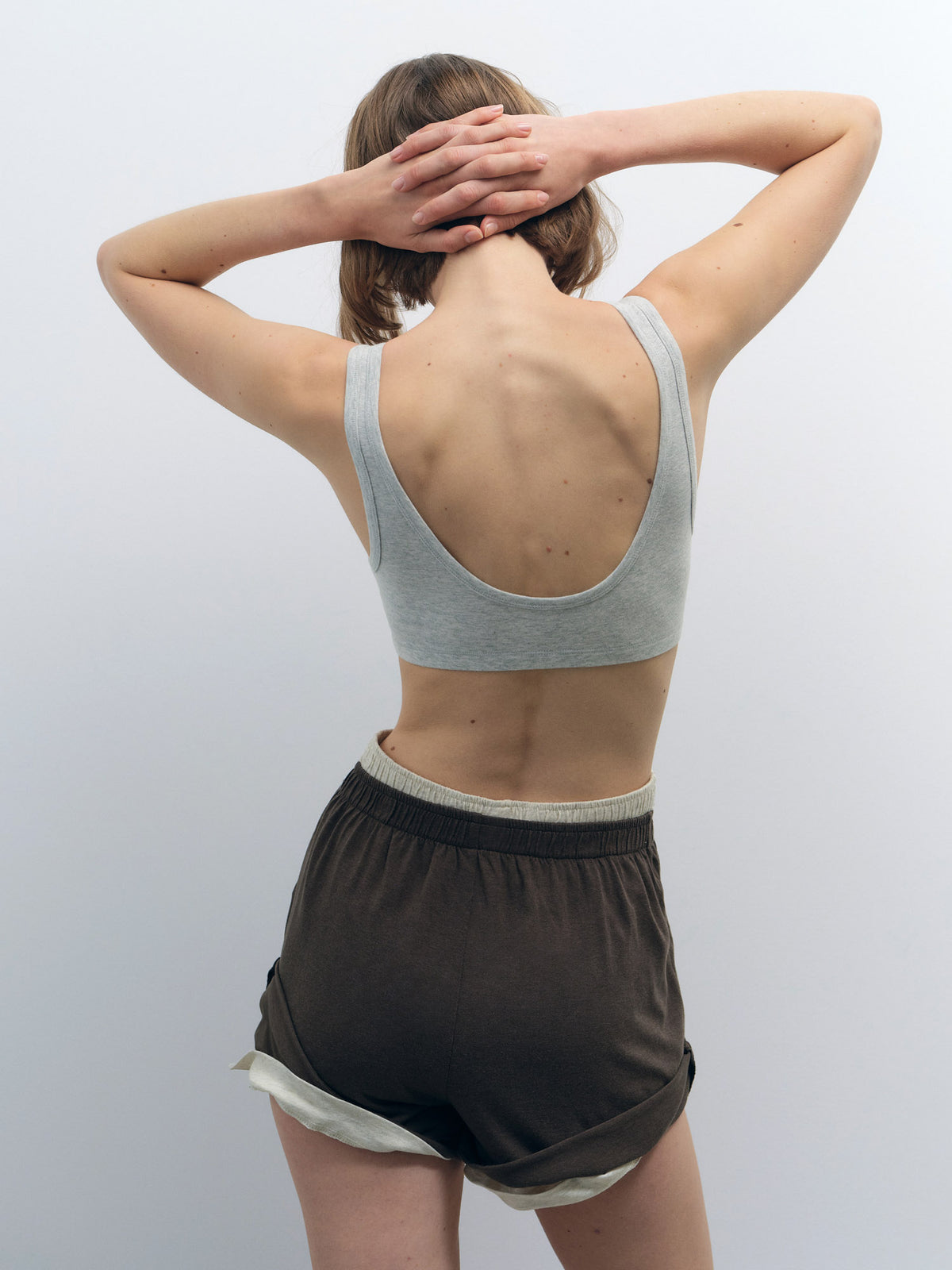 Model from behind wearing a light grey organic cotton scoop bralette with a wide elastic band.