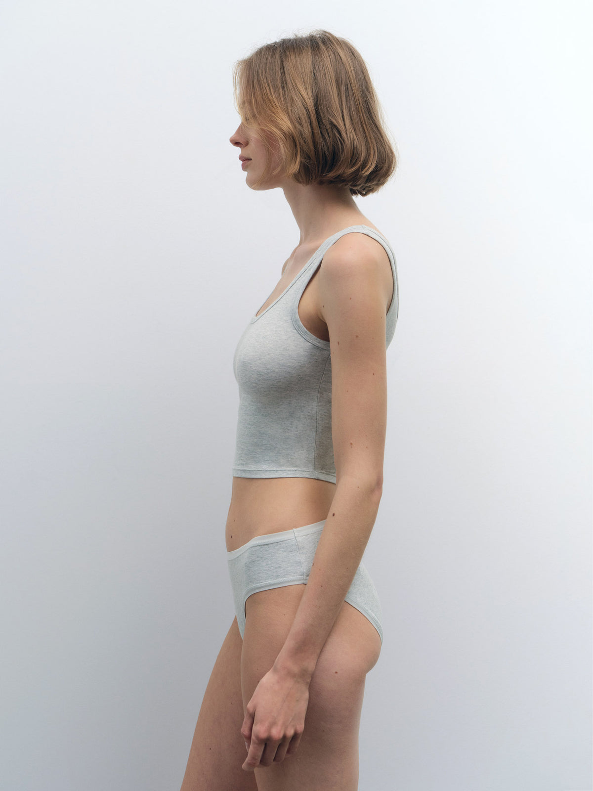 Woman in profile wearing a light gray organic cotton crop tank and matching briefs.