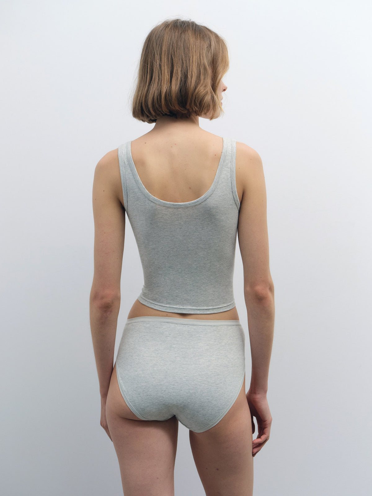 Woman from behind wearing a light grey organic cotton crop tank and matching high-cut briefs.