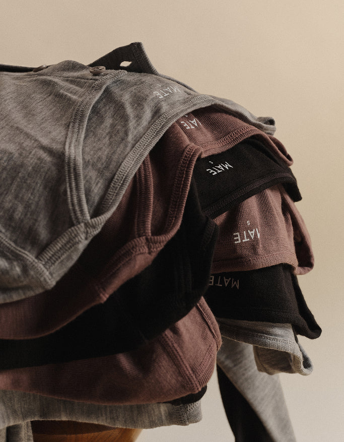 Stack of Mate the Label tank tops in gray, brown, and black on hangers