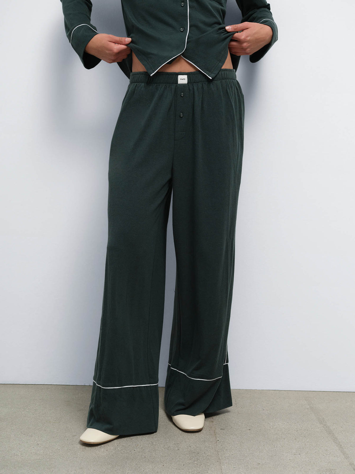 Close-up of the wide-leg pant from the Tencel Sleep Set in Balsam with Heather Grey piping, worn with cream flats