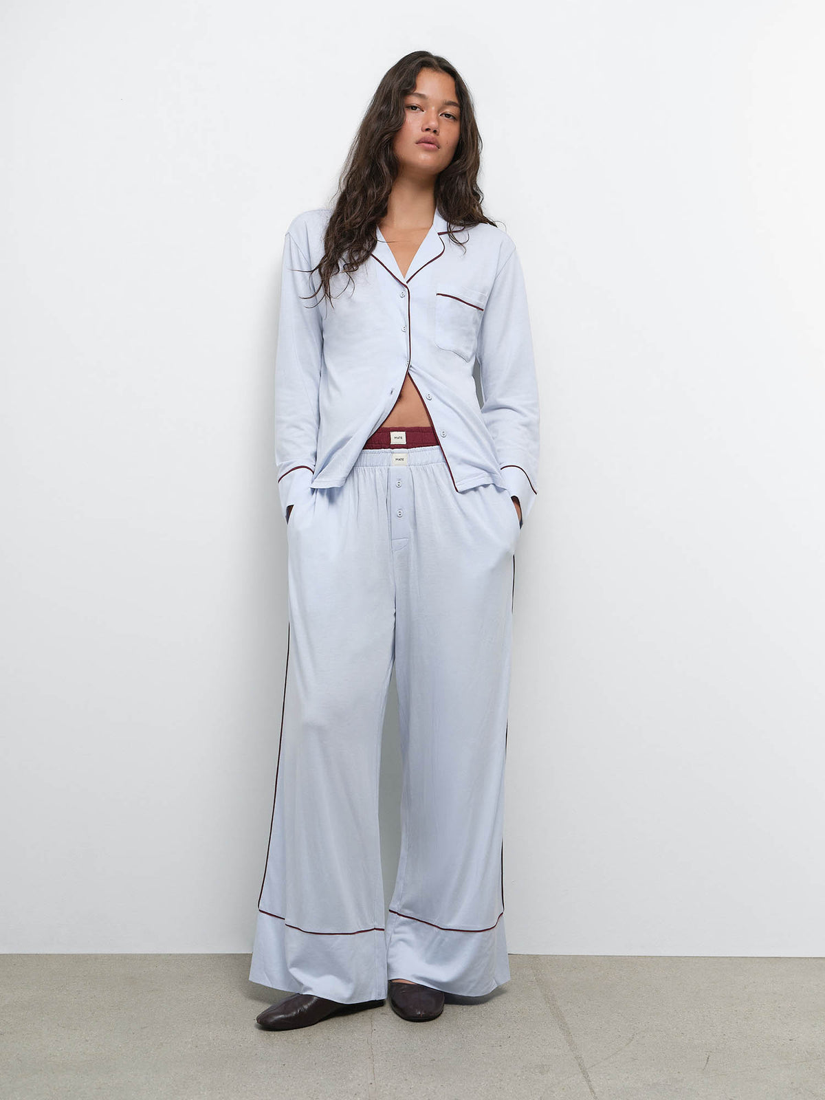Full-length view of model with hands in pockets wearing the Tencel Sleep Set in Powder with Garnet