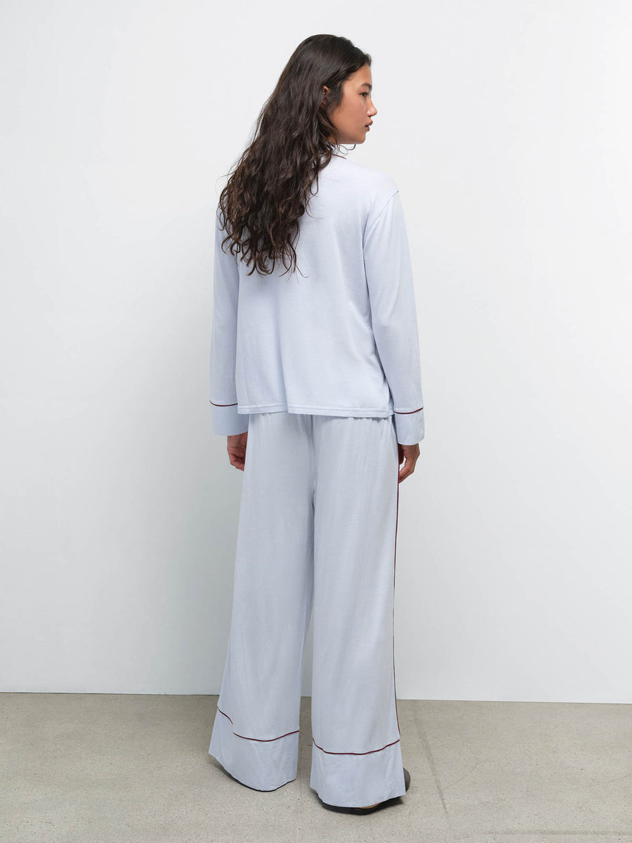 Back view of model wearing the Tencel Sleep Set in Powder with Garnet piping