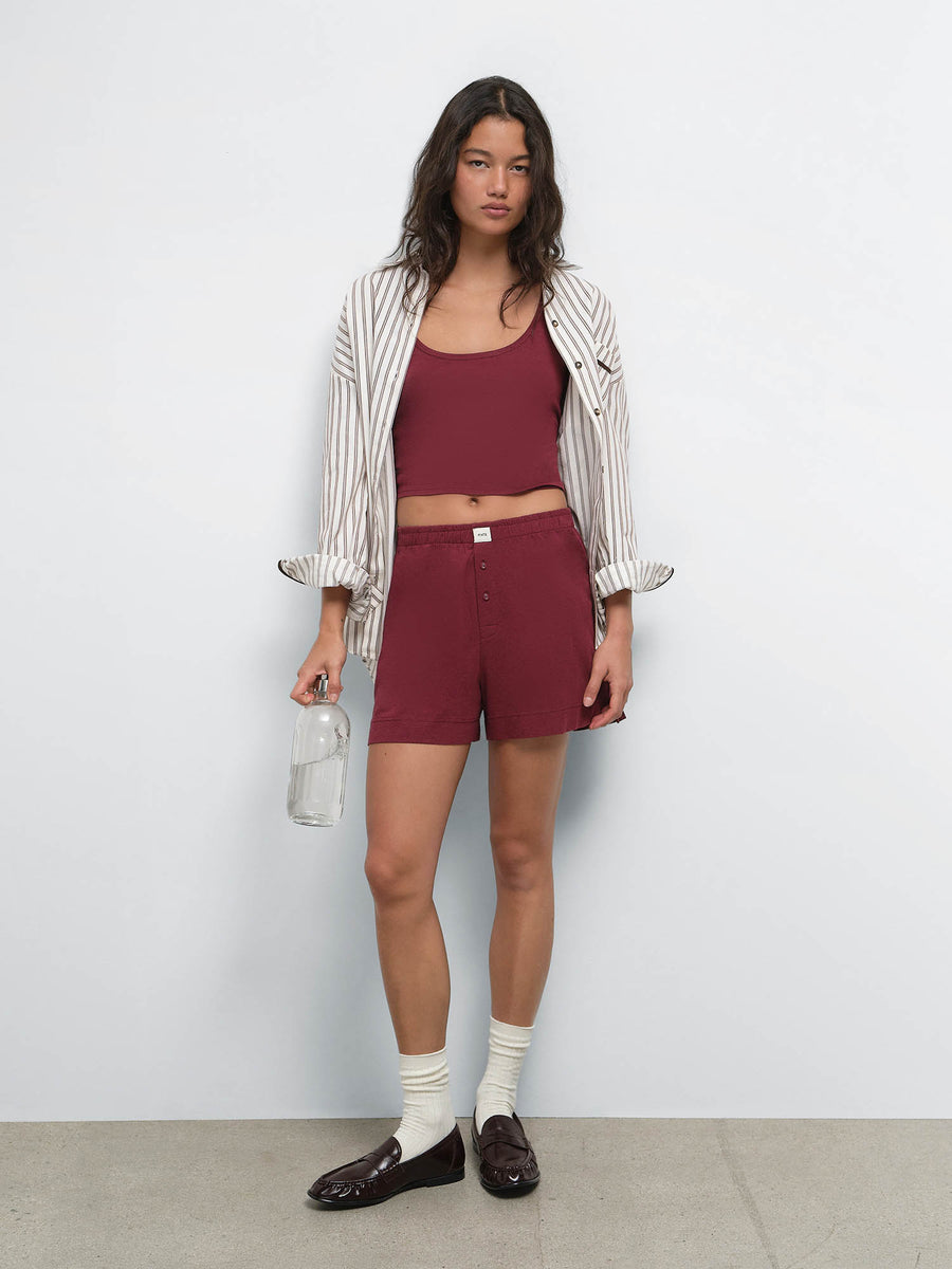 Full-length view of model in a striped shirt over the Tencel Sleep Scoop Tank in Garnet and matching shorts with white socks and loafers