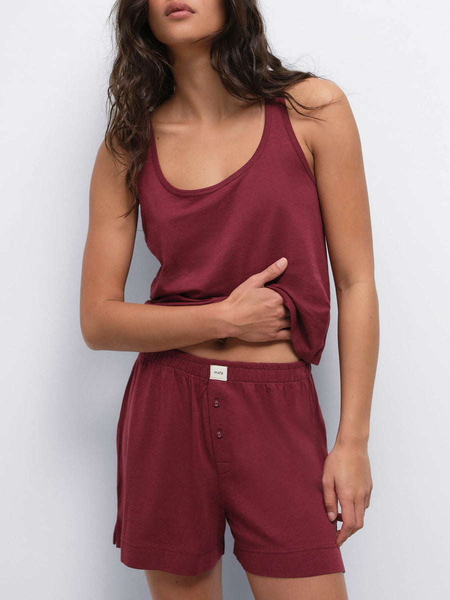 Model with hand at her waist wearing the Tencel Sleep Scoop Tank in Garnet with matching shorts
