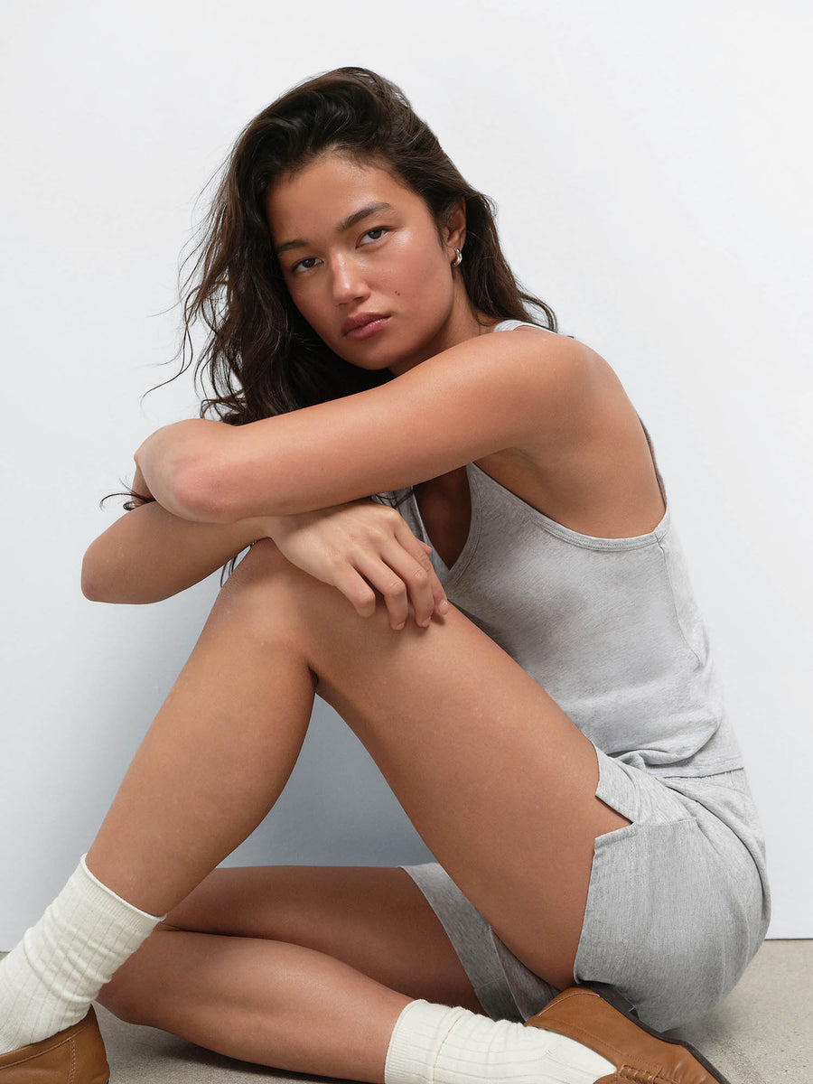Model sitting on the floor in the Tencel Sleep Scoop Tank and Boxer Short in Heather Grey with white socks