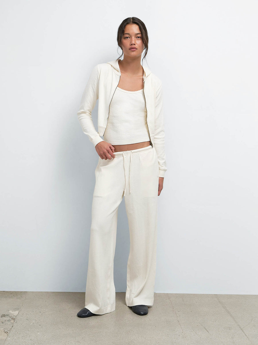Full-length view of model with hands in pockets wearing the Organic Pointelle Shrunken Hoodie, Tank and Pant in Cream