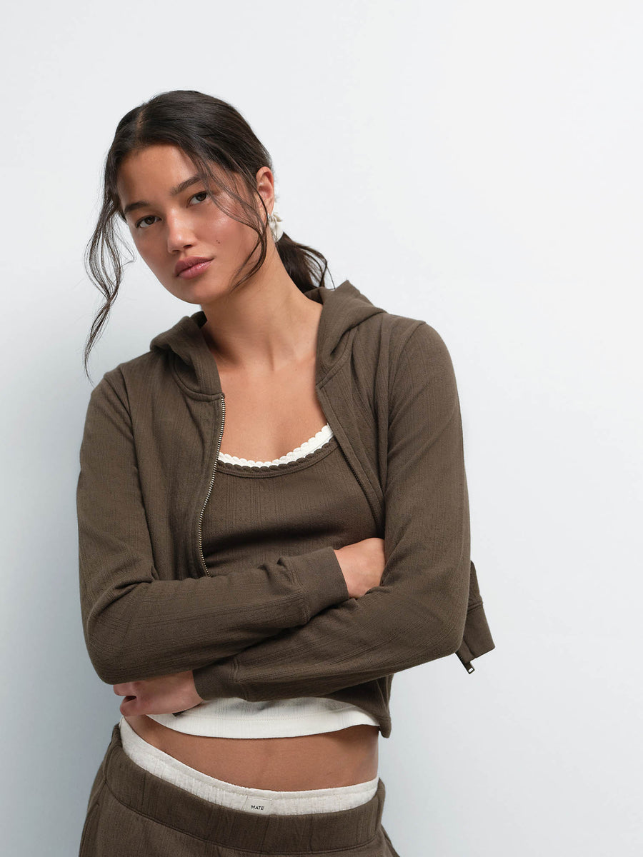 Model with arms crossed wearing the Organic Pointelle Shrunken Hoodie and Jogger in Mocha over a cream tank