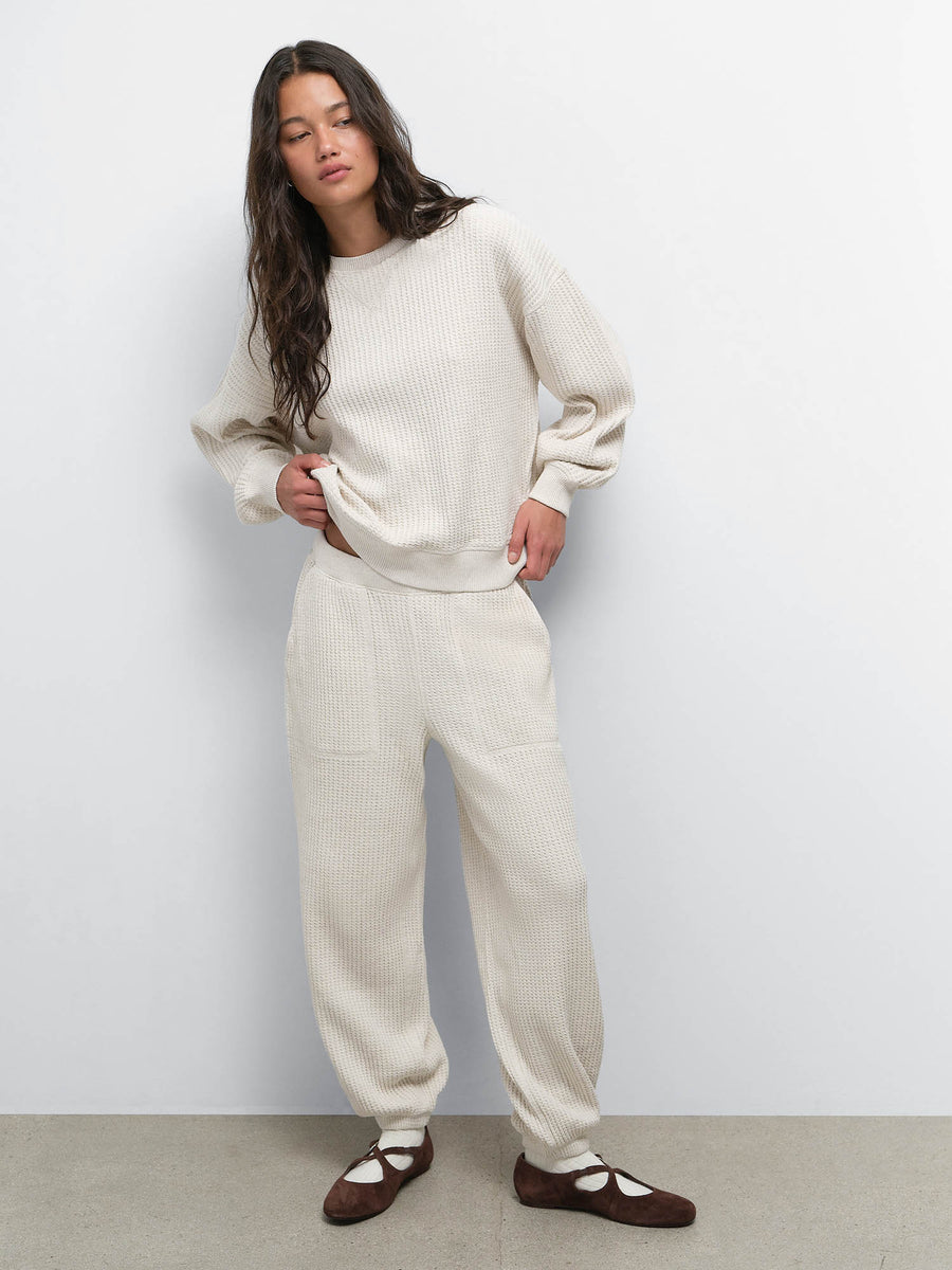 Model with hand on hip wearing the Organic Waffle Crewneck Sweatshirt and Sweatpant in Oat with black Mary Janes