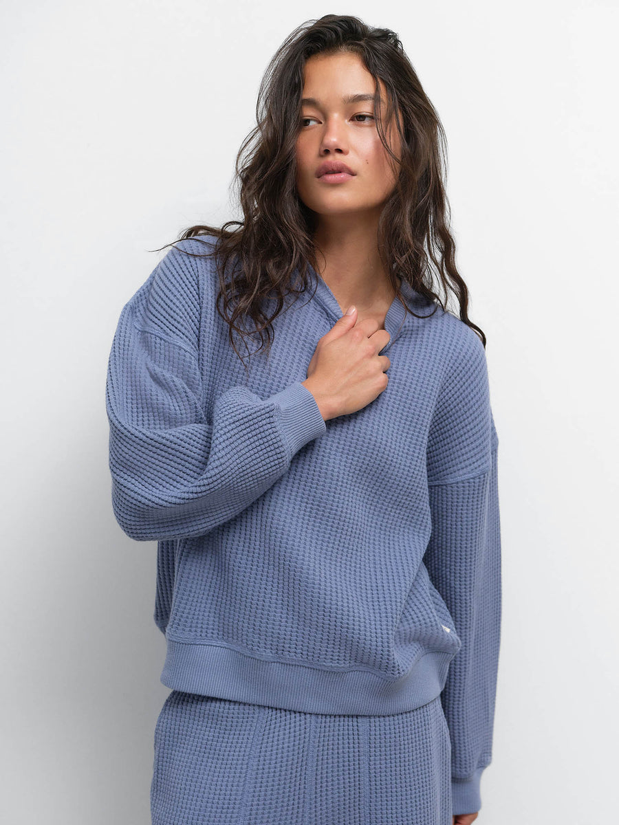 Model with hand on chest wearing the Organic Waffle Crewneck Sweatshirt and Sweatpant in Bay