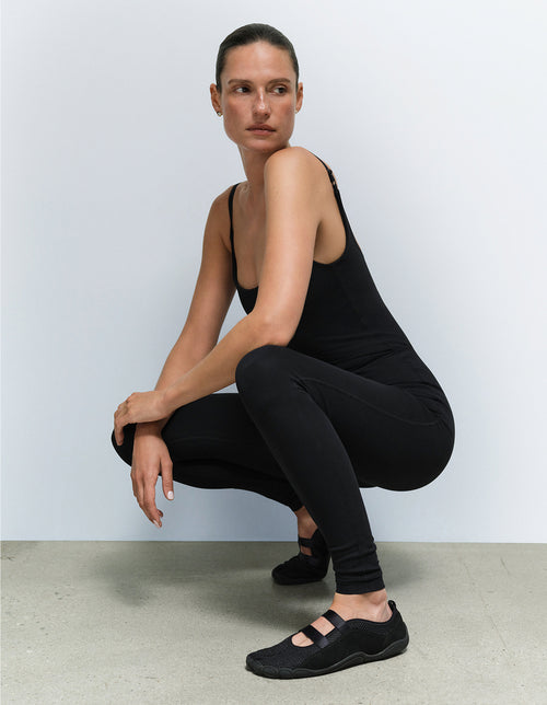 Model wearing a black unitard from Mate the Label, crouching