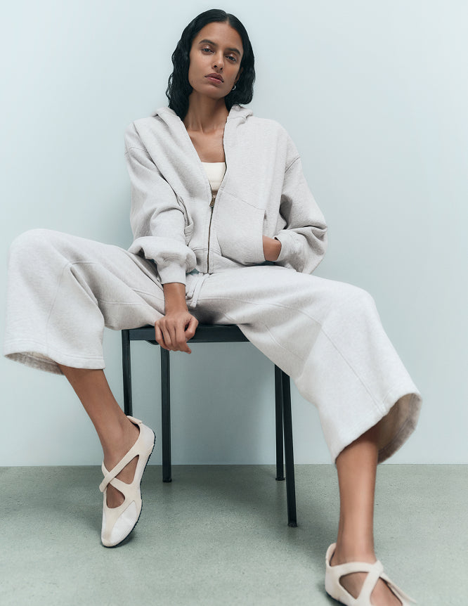 Woman seated in an oatmeal organic zip-up hoodie and wide-leg sweatpants – MATE the Label loungewear