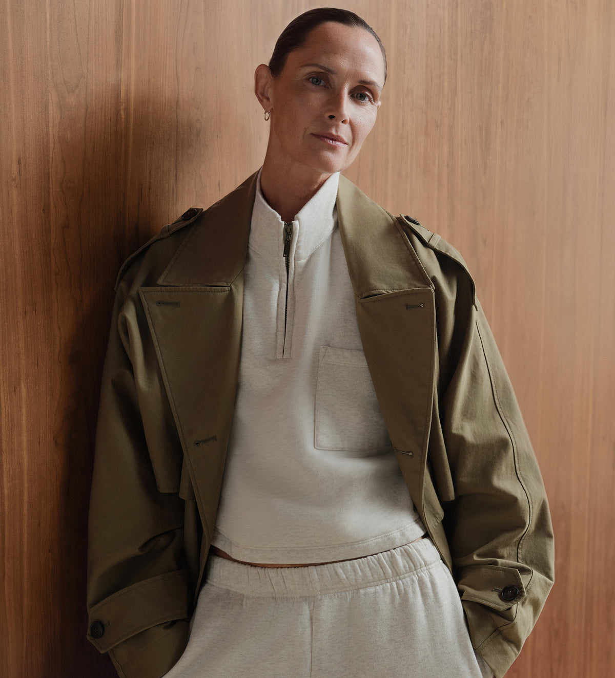 MATE model in coordinating sweatshirt and sweatpants against a wooden wall