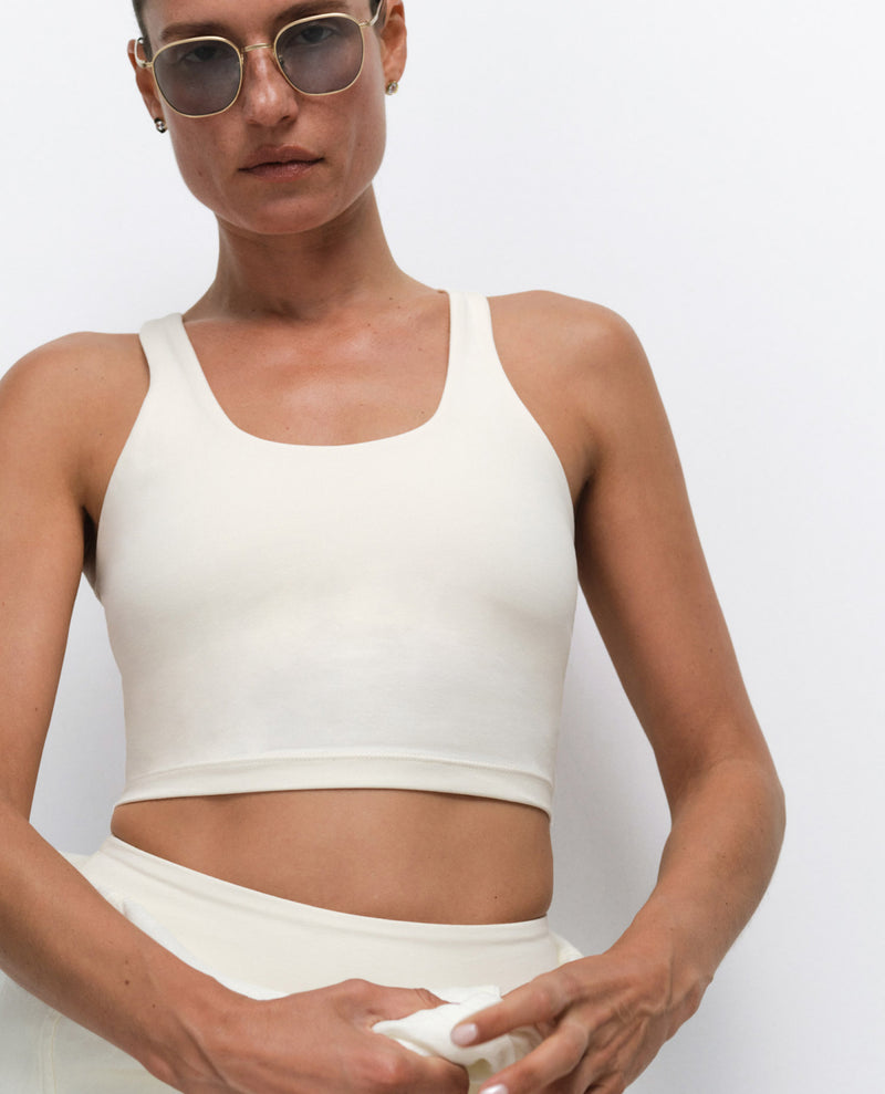MATE model wearing an ivory racerback tank crop top and matching ivory sweatpants, with sunglasses
