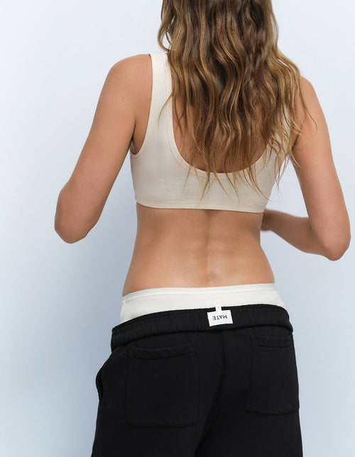 Back view of a MATE model wearing a bone intimates bra top and black sweatpants with a visible MATE waistband tag