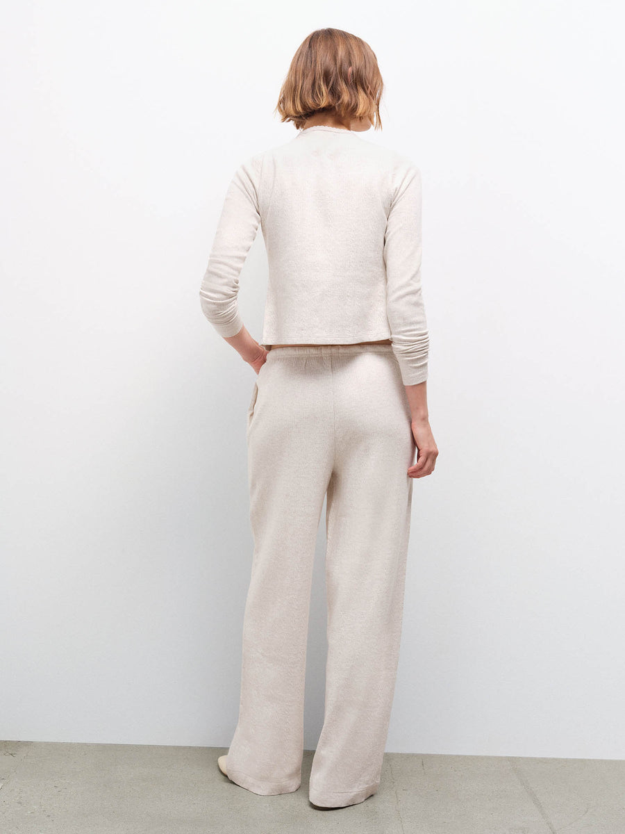 Woman standing wearing a cream pointelle top and matching wide-leg pants, back view in studio