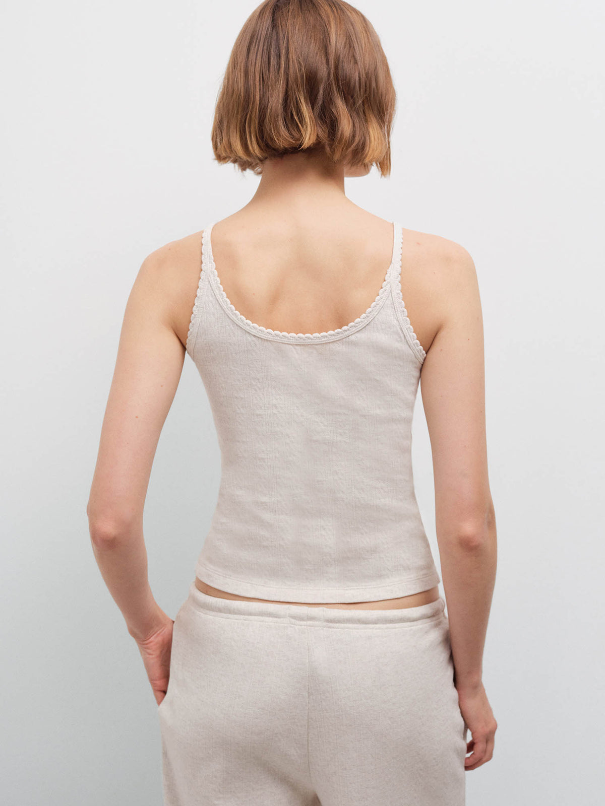 Woman wearing an oatmeal ribbed camisole and matching sweatpants, back view in studio
