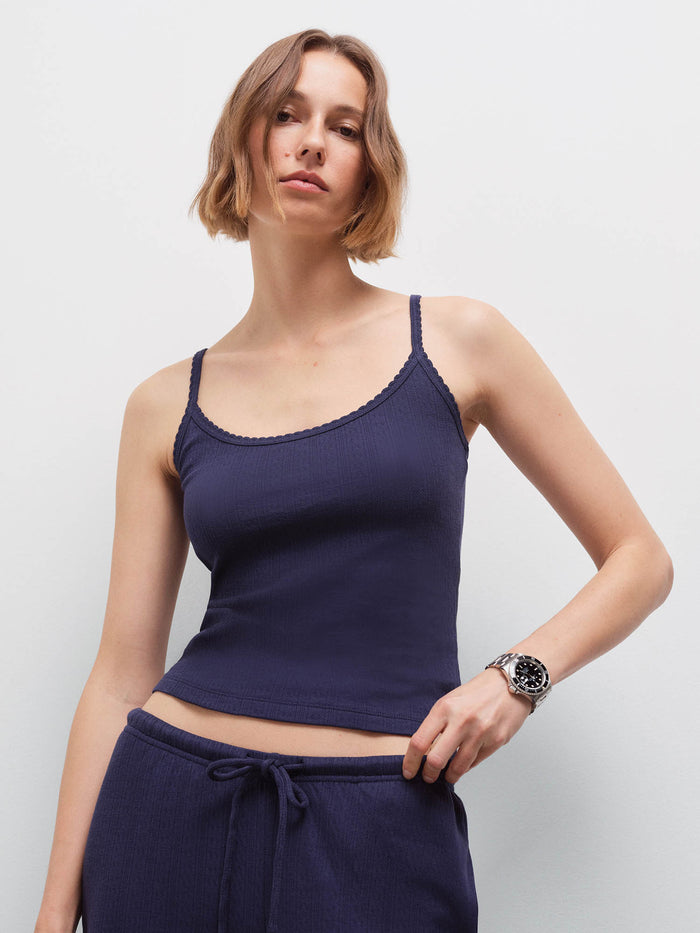 Woman wearing navy pointelle tank and matching pants, front view with hand on hip in studio