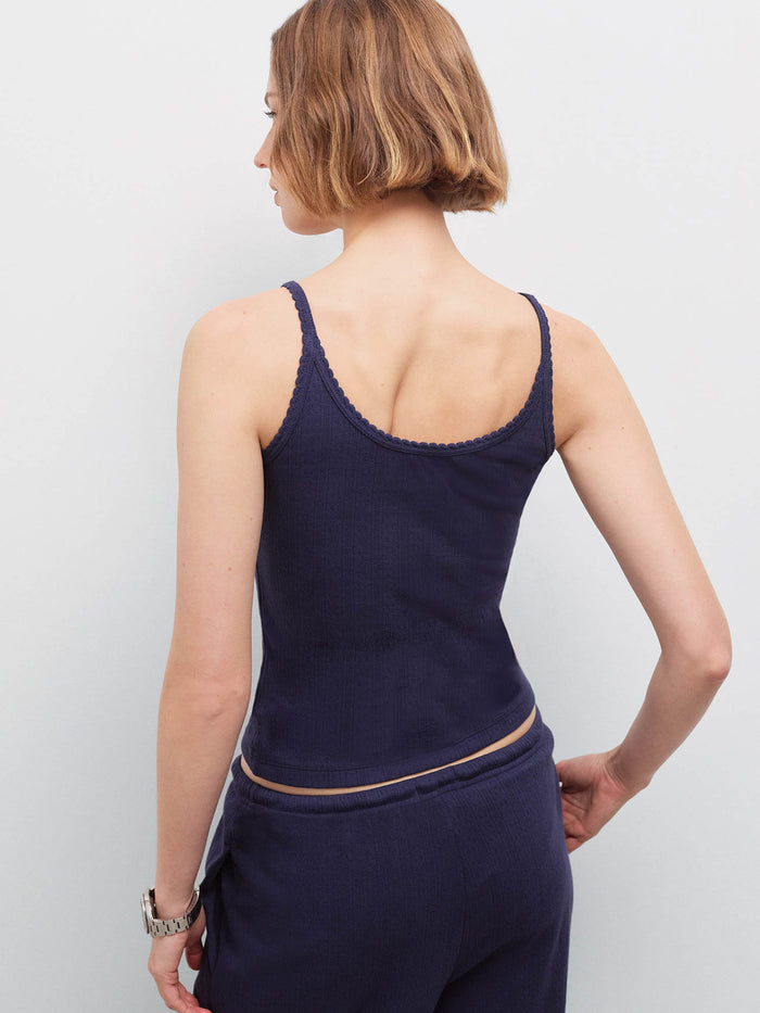 Woman wearing navy pointelle tank, back view showing scalloped neckline and thin straps in studio