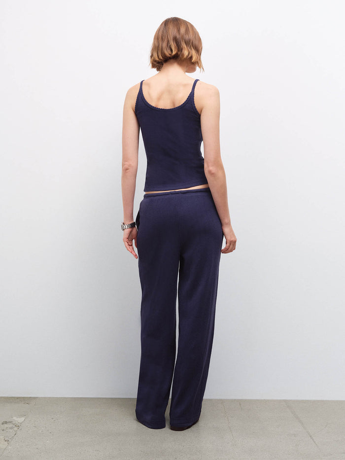 Woman standing wearing a navy pointelle tank top and matching wide-leg pants, back view in studio