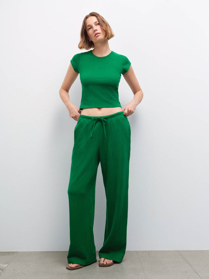 Woman wearing a navy ribbed tank top and matching navy sweatpants, side profile view in studio