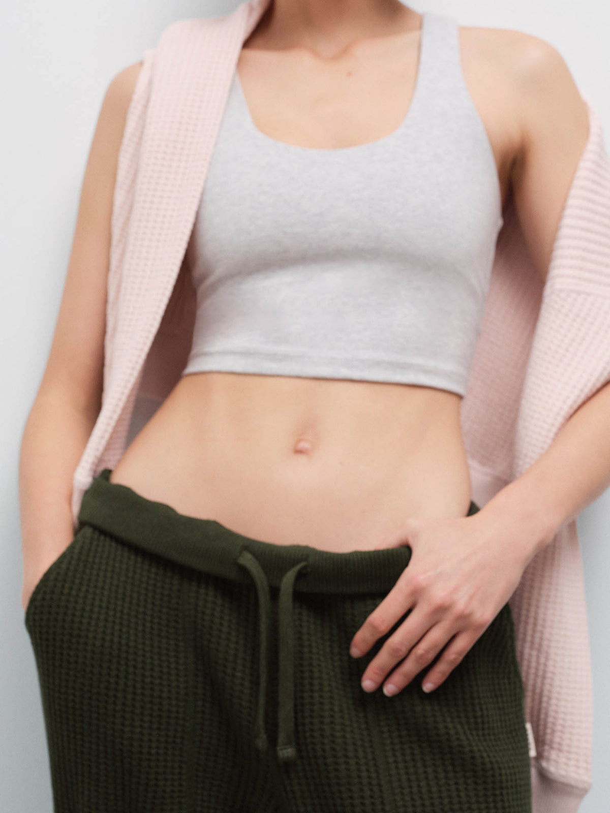 Close-up of a woman's torso wearing a heather gray cropped tank and olive green waffle jogger sweatpants with drawstring waist