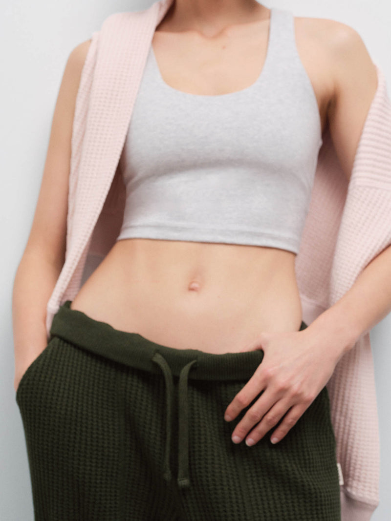 Close-up of a woman's torso wearing a heather gray cropped tank and olive green waffle jogger sweatpants with drawstring waist