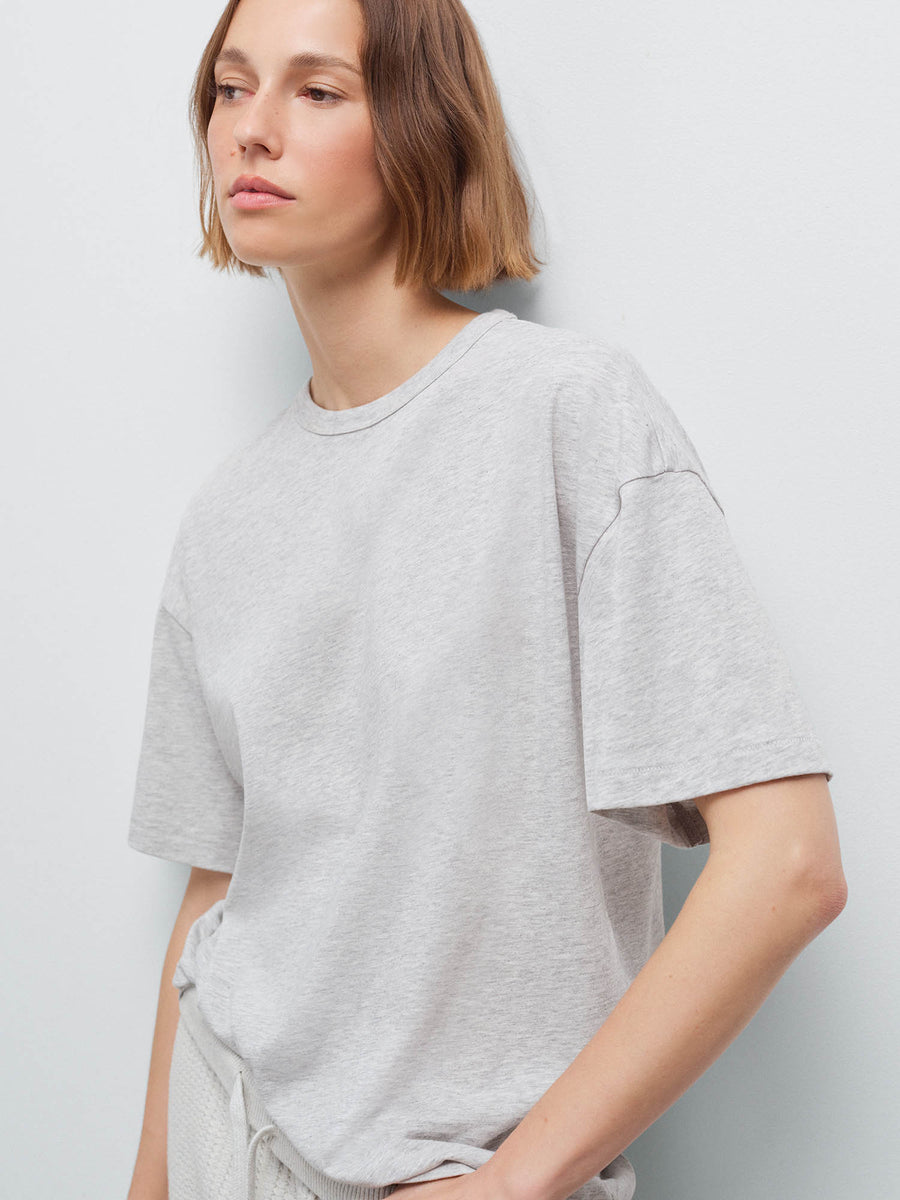 Close-up side view of woman wearing heather grey oversized pima tee, shoulder and sleeve detail in studio