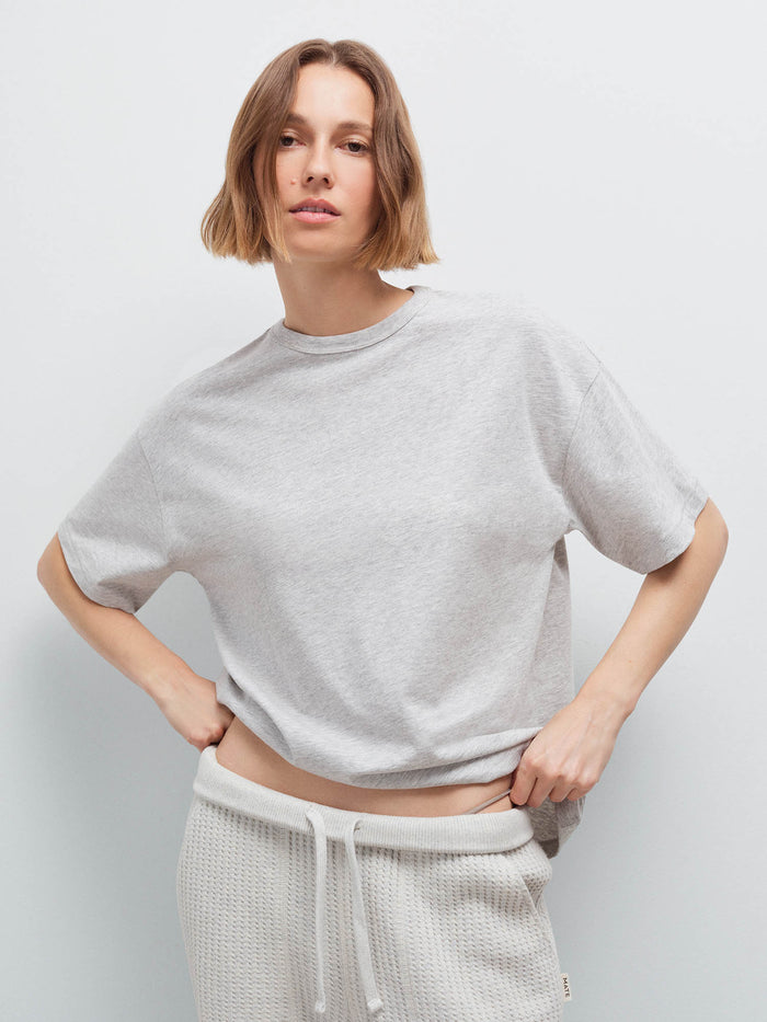 Woman wearing heather grey oversized pima tee with cream waffle-knit sweatpants, front view in studio