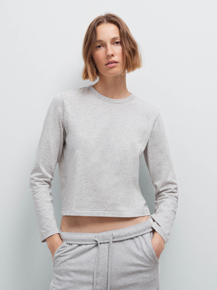 Woman wearing a heather grey long-sleeve cropped top and matching sweatpants, front view in studio