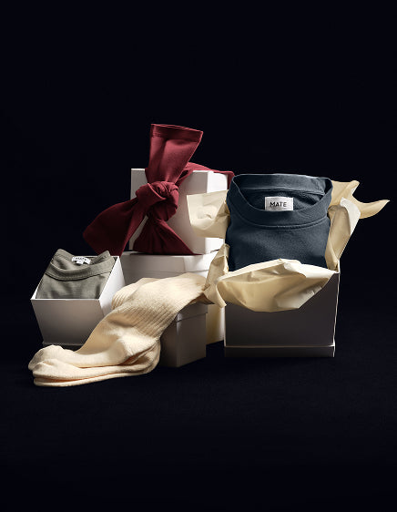 Open gift boxes with folded loungewear and burgundy and cream ribbons – MATE the Label holiday